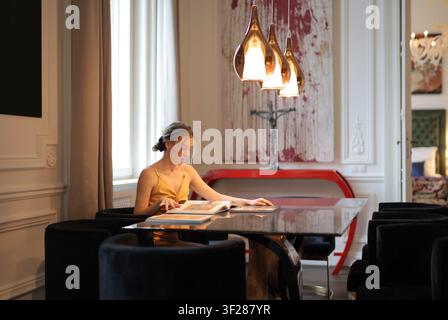 Stylish woman sitting at a table reading a book Stock Photo