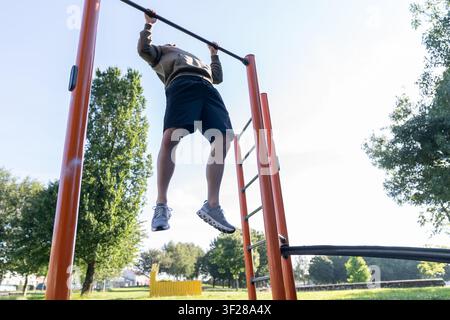 Man doing pullups on outdoor exercise bar Stock Photo