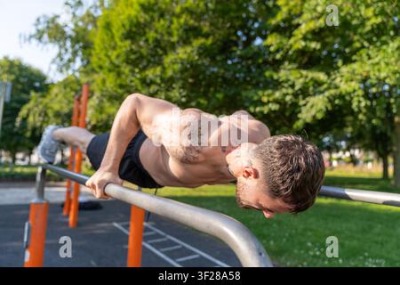 Athletic man doing pushups on parallel bars outdoor Stock Photo