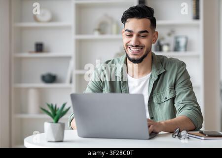Smiling Young Man Working On Laptop At Home Office, Business Concept Stock Photo