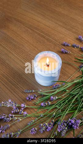 Burning candle blue ceramic jar fresh lavender flower bouquet wooden table top view. Vertical frame empty copy space text template advertisement Stock Photo