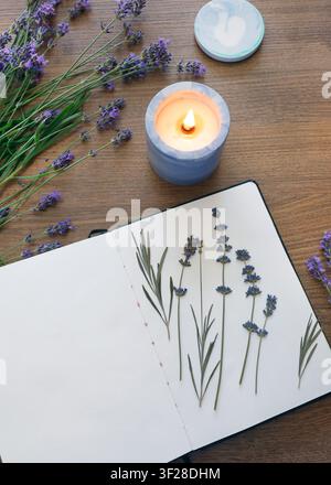 Open notebook blank page herbarium dried lavender flower burning candle wooden table. Top view craft paper sketchbook hobby diary template mockup copy Stock Photo