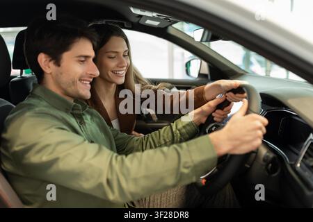 Happy Young Couple Testing Car Together, Smiling Inside Vehicle, Automotive Concept Stock Photo