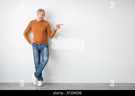 Smiling Senior Caucasian Man Pointing With Finger, Modern Indoor Space, Lifestyle Concept Stock Photo