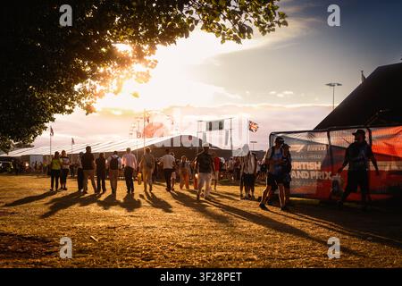 Fans in the evening at Silverstone during the British Grand Prix weekend, walking through the entertainment area in warm sunset light. Stock Photo