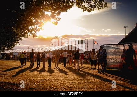 Fans in the evening at Silverstone during the British Grand Prix weekend, walking through the entertainment area in warm sunset light. Stock Photo
