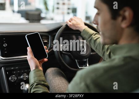 Unrecognizable Man Using Smartphone While Driving A Car, Focused On Mobile Device Stock Photo