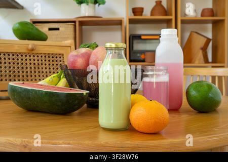 Fresh fruits and homemade drinks arranged on a wooden table in a modern home setting. Nutrition, wellness, and healthy living concept. Stock Photo