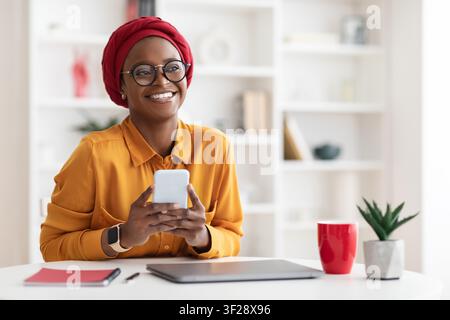 Smiling Black Woman Using Smartphone In Modern Office, Business Concept Stock Photo