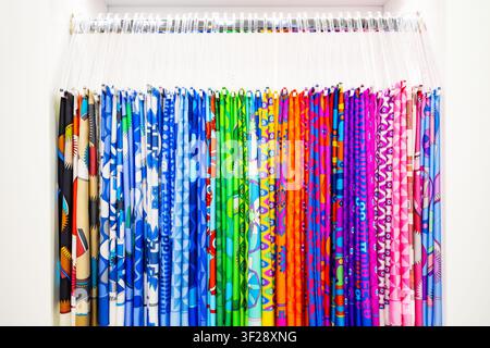 Large collection of colorful silk scarves hanging on transparent hangers inside white boutique wardrobe Stock Photo