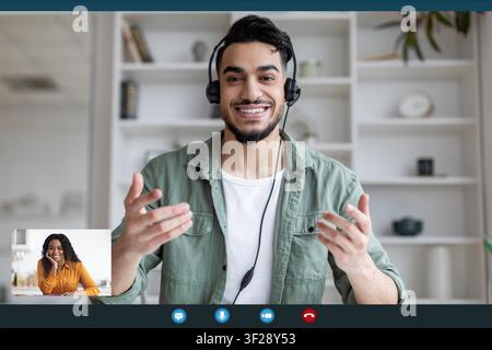 Smiling Young Arab Man In Headset Communicating Online, Remote Work Concept Stock Photo