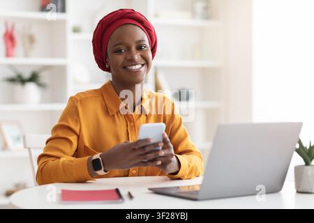 Smiling Black Woman Using Smartphone In Office, Business Concept Stock Photo