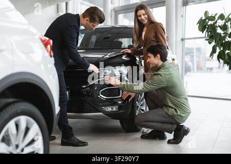 Young Multiracial Group Examining Black Suv In Car Dealership, Positive Emotion, Business Concept Stock Photo