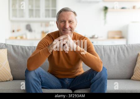 Smiling Mature Caucasian Man Relaxing On Sofa At Home, Lifestyle Concept Stock Photo