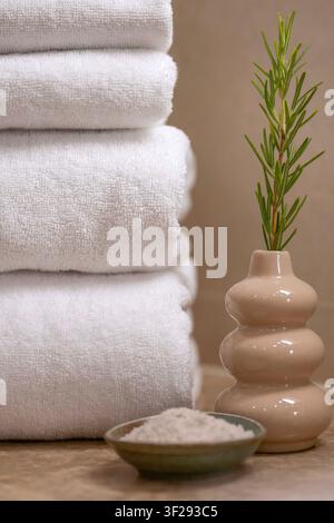 Rolled white towel on a wooden bath tray with spa essentials in a modern hotel bathroom, creating a relaxing wellness atmosphere Stock Photo