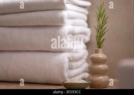 Rolled white towel on a wooden bath tray with spa essentials in a modern hotel bathroom, creating a relaxing wellness atmosphere Stock Photo