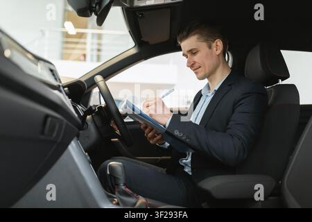 Businessman Writing In Notebook Inside Car, Deal Negotiation Concept Stock Photo
