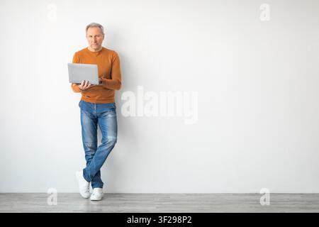 Elderly Caucasian Man Using Laptop While Standing, Home Office Concept Stock Photo
