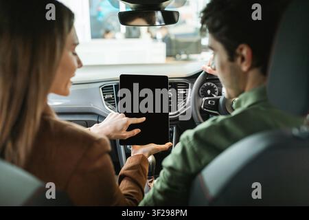 Young Caucasian Woman And Man Using Tablet In Car, Engaged In Conversation Stock Photo