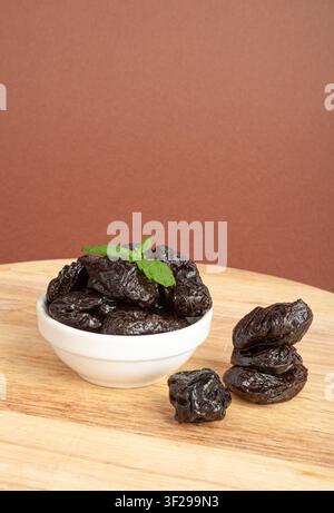 Dry Plums, Dried Black Fruits in Bowl, Prune Group, Natural Dessert, Healthy Diet, Dry Plum Fruit on Wooden Table Background Stock Photo