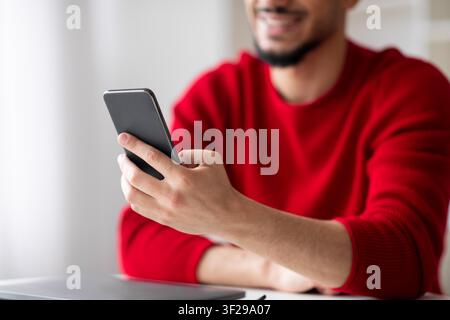 Smiling Young Male Using Smartphone In Office, Relaxed State, Business Concept Stock Photo