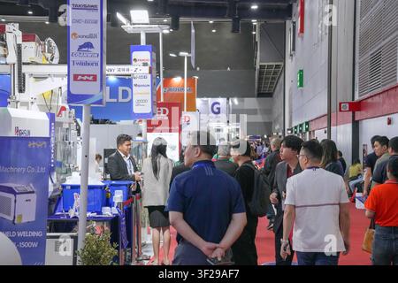 Bangkok, Thailand - June 17, 2026: Visitors gathered near a handheld welding machine display at a manufacturing equipment booth during a trade show. Stock Photo