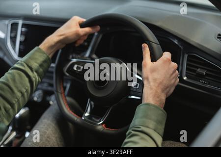 Man Driving Car With Focused Expression, Hands On Steering Wheel, Modern Vehicle Interior Stock Photo