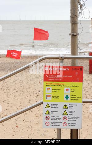 Beach management sign and red flag, signifying 'do not swim' , on beach at Clacton on Sea, Essex, UK Stock Photo