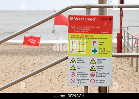 Beach management sign and red flag, signifying 'do not swim' , on beach at Clacton on Sea, Essex, UK Stock Photo