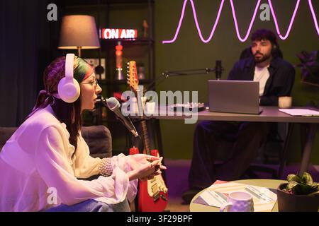 Young Woman Recording Podcast Interview in Creative Studio Stock Photo
