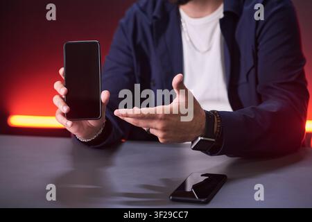 Unknown Man Presenting Smartphone Mockup for Mobile App Marketing Stock Photo