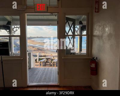 View of Block Island beach seen from an interior doorway with a wooden picnic table on the deck, New Shoreham, Rhode Island, United States. Stock Photo