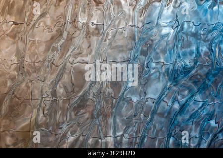 Wavy glass texture in warm gold and cool blue tones, abstract fluid pattern background for design Stock Photo