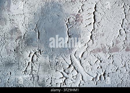 Grey textured concrete wall with deep cracks, plaster scratches, and weathered grunge surface. Stock Photo