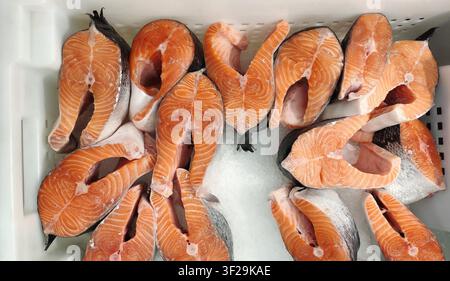 Fresh raw salmon steaks on crushed ice in plastic container Stock Photo