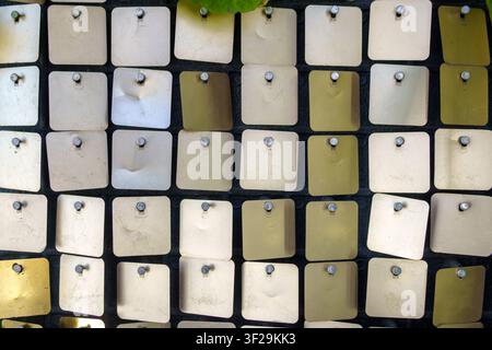 Small square metal sequins fixed with pins on a dark background. Shimmering matrix wall panel texture with silver and gold metallic pieces. Stock Photo
