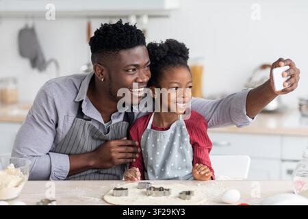 Happy Black Father And Daughter Baking Together At Home, Smiling In Kitchen Stock Photo