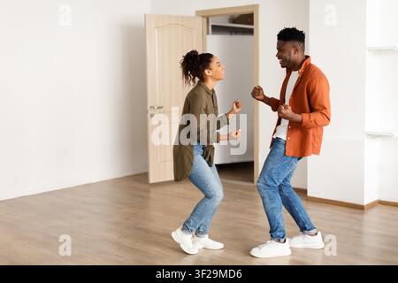Happy Black Couple Dancing Together In New Apartment, Joyful Moment Stock Photo