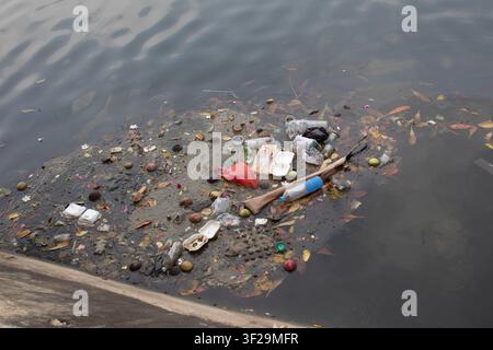 Plastic bottle and household waste floating on the river Jakarta, Indonesia. Water pollution Stock Photo