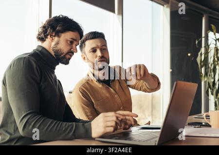 Two Men Collaborating At Office Computer, Focused On Work, Business Concept Stock Photo