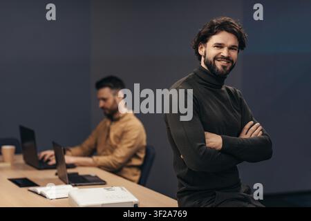 Smiling Young Caucasian Man In Turtleneck Sweater Posing In Office, Workplace Concept Stock Photo