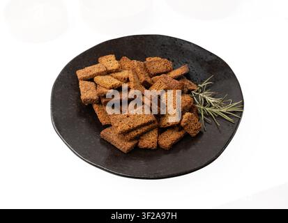 Rye Croutons on Black Plate Isolated, Homemade Brown Bread Rusks, Crispy Bread Cubes Scattered Pile, Dry Rye Crouoton Crumbs, Brown Roasted Salted Cra Stock Photo