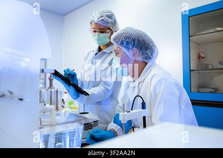 Asian scientists team checking pharmaceutical research data on digital tablet inside modern science laboratory concept of medical clinical development Stock Photo