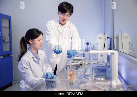 Young asian scientists conducting chemical experiment in laboratory. Science students collaborating on biology project. Scientific education and resea Stock Photo