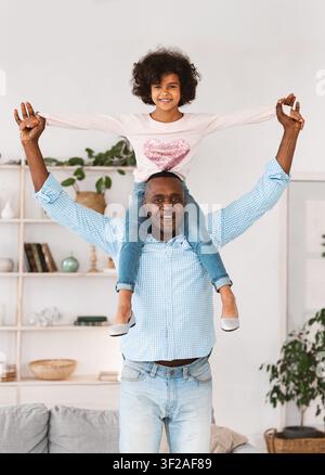 Funny games with granddad. Senior African American man carrying his granddaughter on shoulders at home Stock Photo
