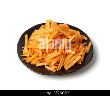 Fried chips sticks on black plate isolated, finger potato chips, golden shoestring fries pile, French fries, roasted potatoes heap, frites on white ba Stock Photo