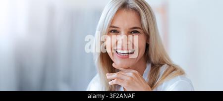 Happy Mature Caucasian Woman Smiling With Hands On Chin, Office Setting, Business Concept Stock Photo