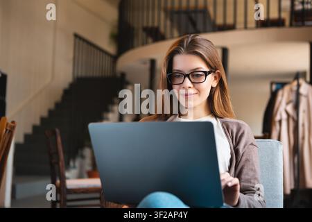 Focused Young White Woman Working On Laptop In Modern Office Space Stock Photo