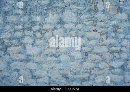 Close-up of an old weathered stone wall with blue-gray mortar, showing rough texture and natural stone patterns, ideal for backgrounds and constructio Stock Photo