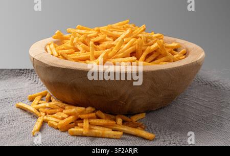 Fried chips sticks, finger potato ketchup flavored chips in wood bowl, golden shoestring fries pile, French fries, roasted potatoes heap, frites close Stock Photo